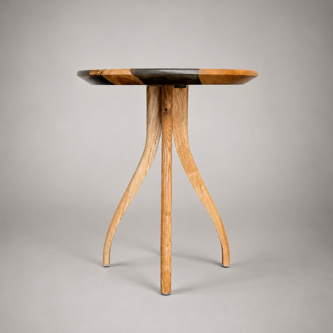 A small round wooden side table with a natural wood grain top and three curved legs, photographed against a neutral gray studio background.